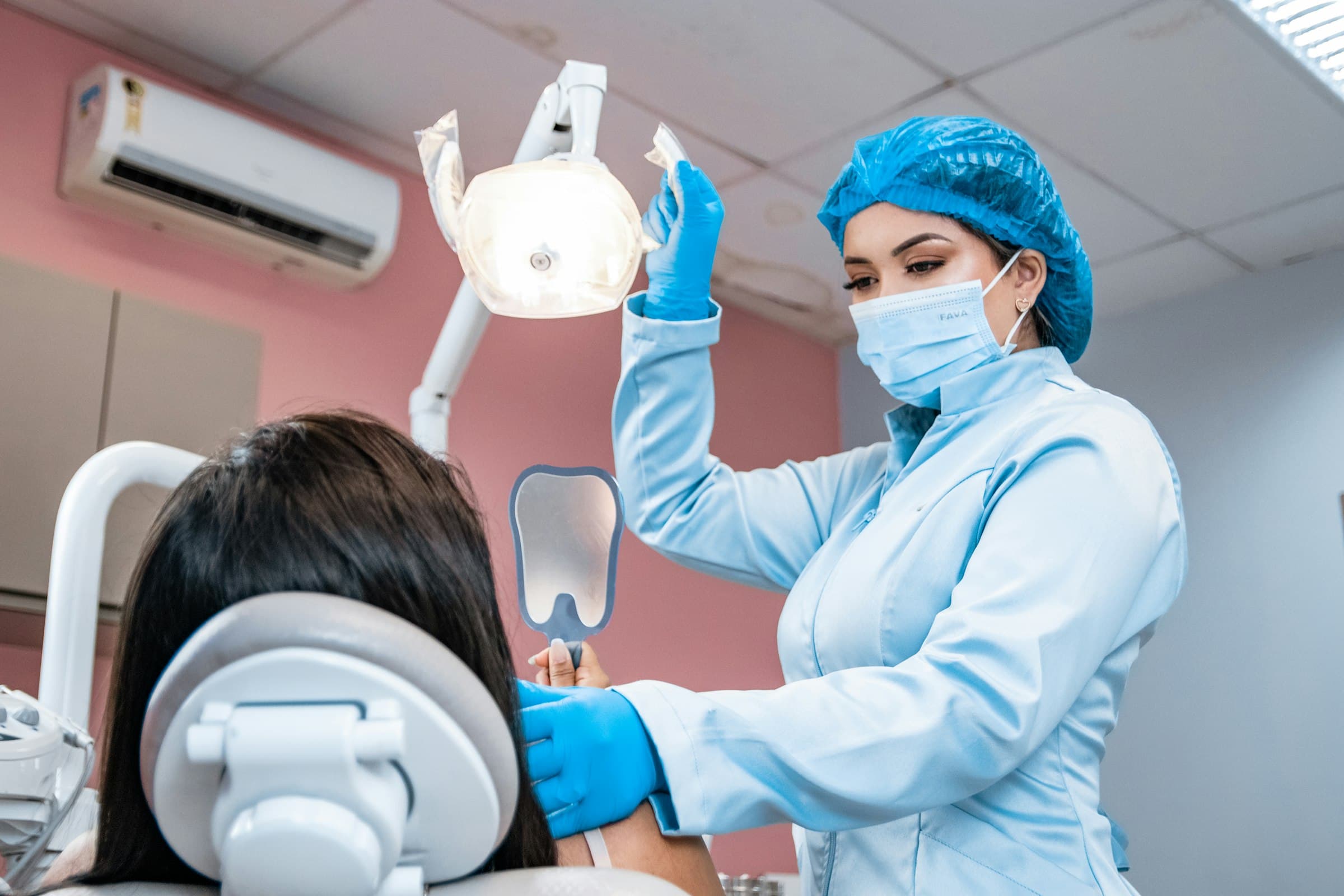 A dental professional examining a seated patient during an oral checkup in a brightly lit dental practice.
