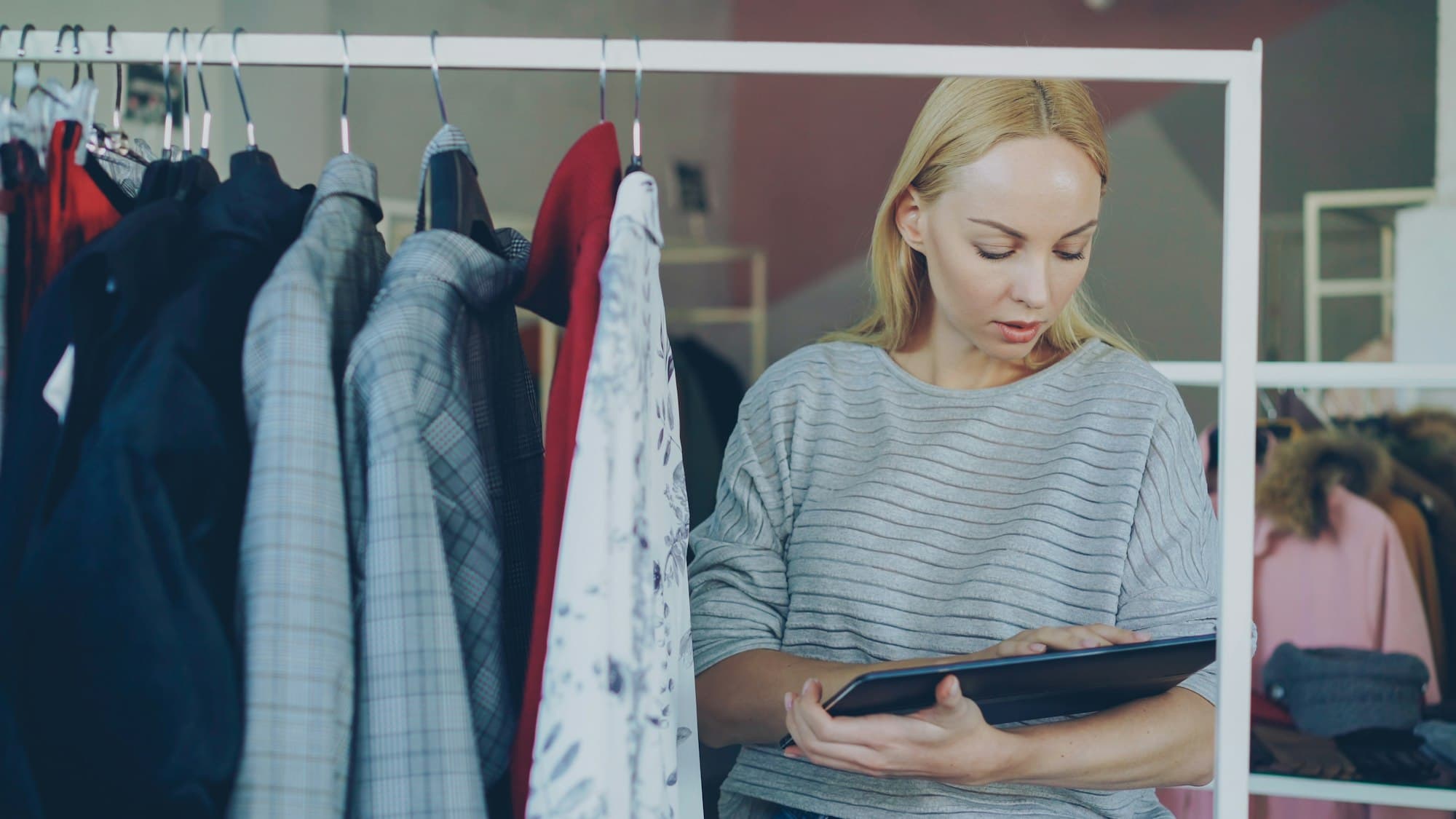 A boutique owner reviewing inventory on a tablet on her shop floor.